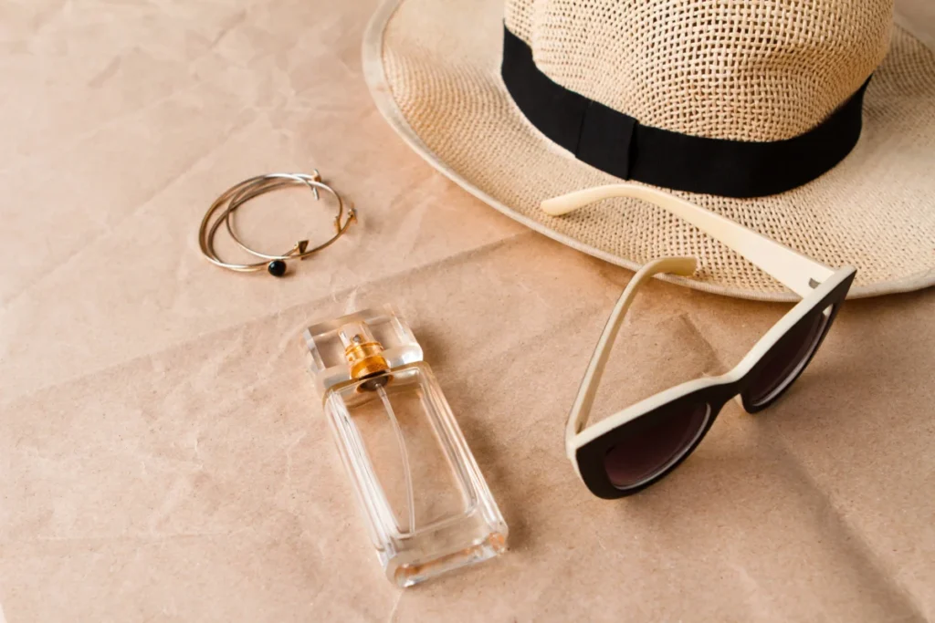 chapéu de praia, brincos, óculos de sol e perfume em evidência - perfumes importados femininos mais vendidos