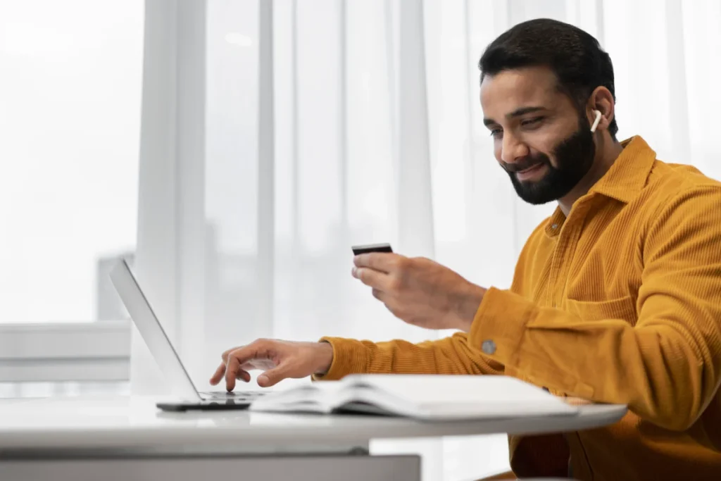 homem trabalhando no computador enquanto mexe no celular como começar a vender na internet