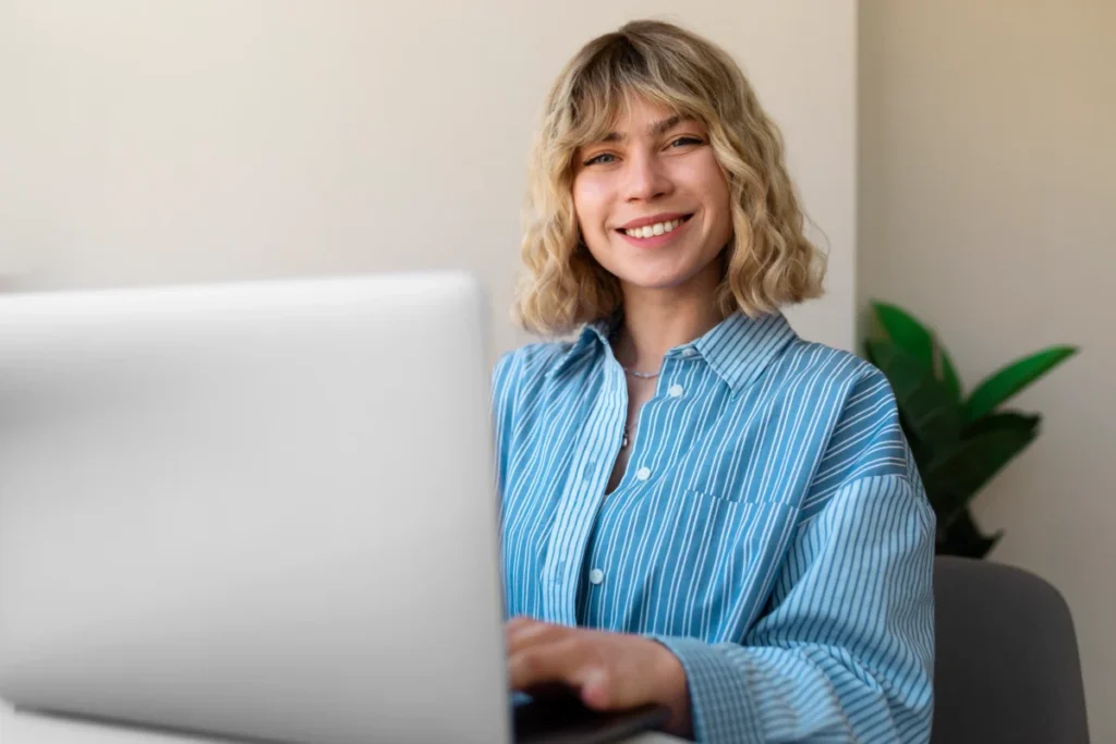 mulher sorridente em frente ao computador quero montar uma loja virtual o que vender